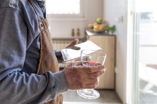 Чоловік з келихом для вина тримає цифровий планшет вдома — стокове фото