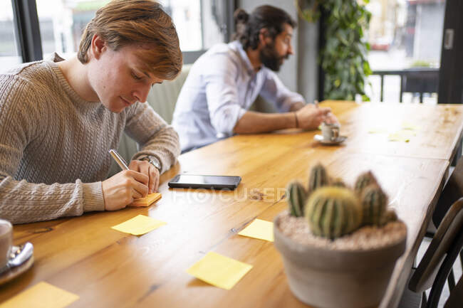 Stratégie d'écriture jeune homme d'affaires assis au bureau — Photo de stock
