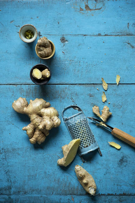 Ginger Root Grater Small Cups And Kitchen Knife Lying On Blue Wooden Surface Healthy Preparation Stock Photo