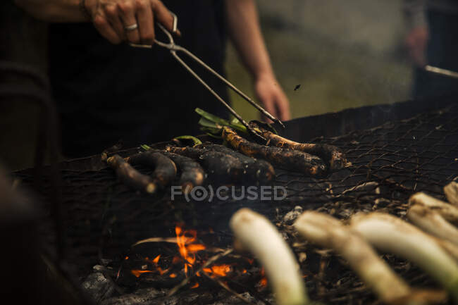 Ragazzo adolescente utilizzando pinze di servizio durante la cottura calli sul barbecue in piedi all'aperto — Foto stock