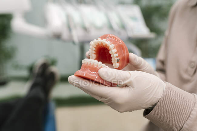 Medico con guanto protettivo che tiene la dentiera in clinica — Foto stock