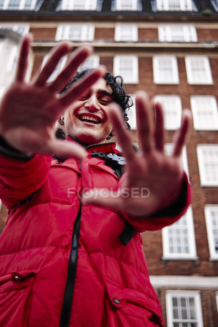 Homme heureux montrant les mains contre la construction — Photo de stock