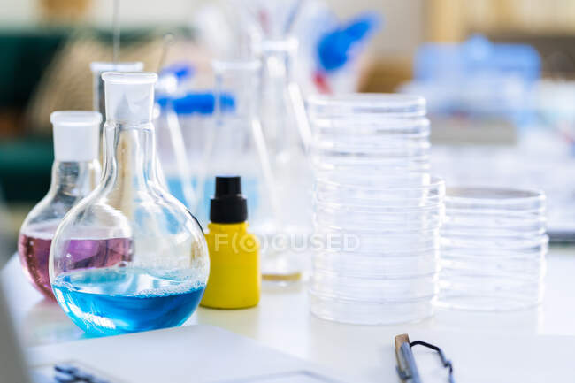Vasos de precipitados con solución química en la mesa del laboratorio - foto de stock