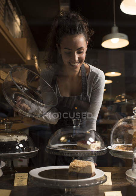 Glückliche Inhaberin betrachtet süßes Essen bei der Arbeit in der Bäckerei — Stockfoto