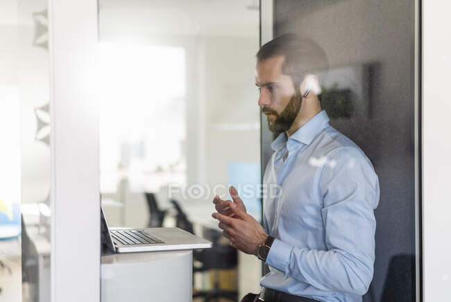 Male professional having discussion on video call over laptop in telephone booth at office — Stock Photo