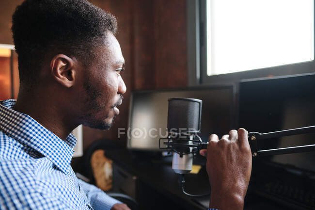 Взрослый влиятельный человек держит микрофон во время подкаста дома — стоковое фото