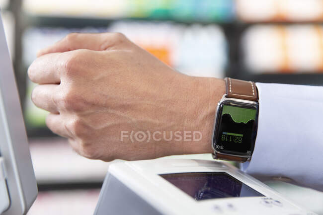 Male customer doing contactless payment through smart watch at — 50 60 years, shop - Stock Photo | #482789330