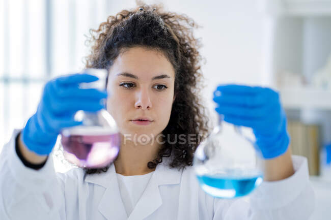 Solución química de ensayo médico femenino en vaso de precipitados en laboratorio - foto de stock
