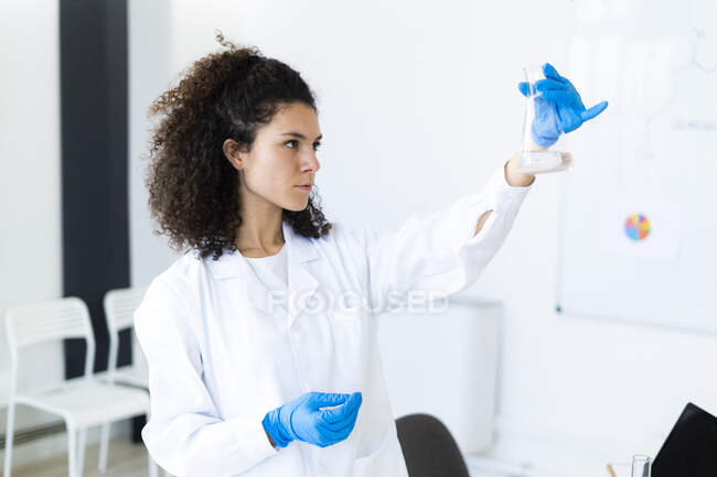 Femme scientifique confiante examinant une solution chimique à l'hôpital — Photo de stock