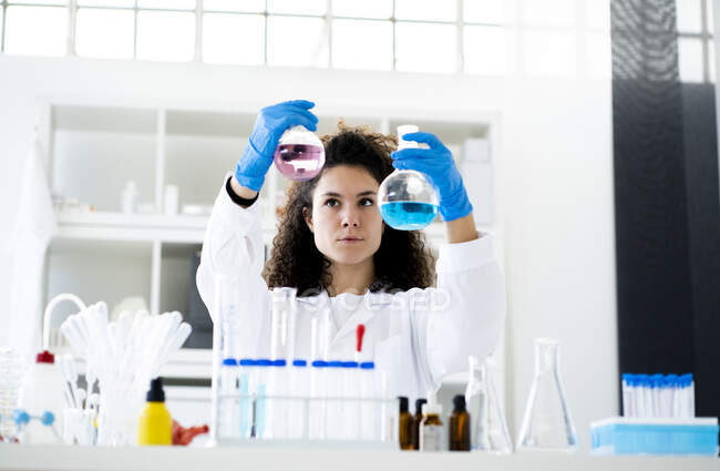 Chercheur femelle vérifiant la solution chimique dans le bécher au laboratoire — Photo de stock