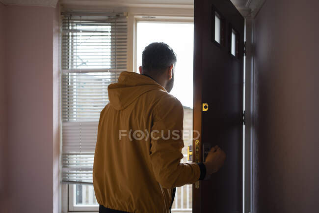 Hombre de chaqueta amarilla abriendo puerta — Stock Photo