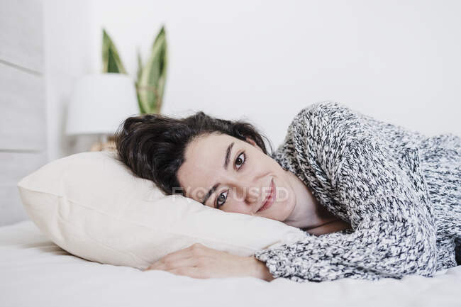 Femme souriante reposant sur le lit à la maison — Photo de stock