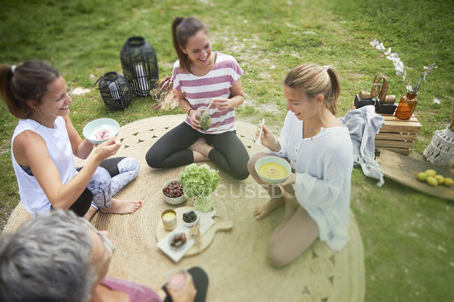 Smiling female friends having food while sitting on meadow — Stock Photo