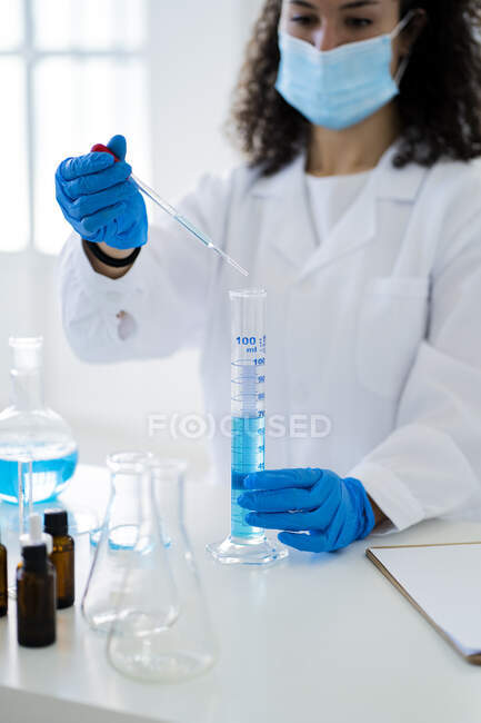 Pesquisadora fêmea misturando solução química em tubo de ensaio através de pipeta em laboratório — Fotografia de Stock