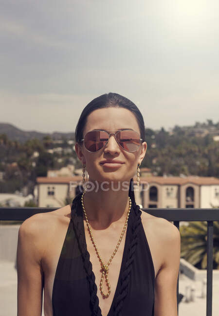 Jovem mulher usando óculos de sol e roupa de banho sorrindo ao ar livre — Fotografia de Stock