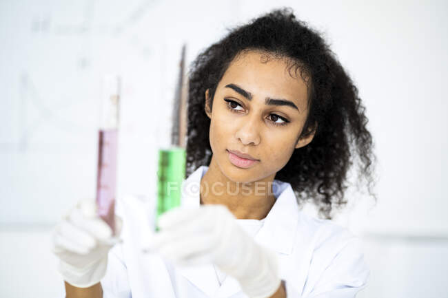 Chimica femminile che esamina il liquido nelle provette mentre lavora in laboratorio — Foto stock