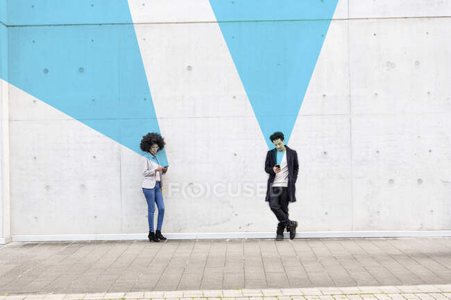 Visualización gráfica de los efectos de reconocimiento facial que cubren al hombre y a la mujer utilizando teléfonos inteligentes al aire libre - foto de stock