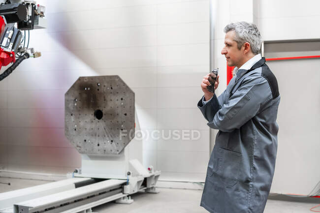 Travailleur examinant les machines debout dans l'usine — Photo de stock