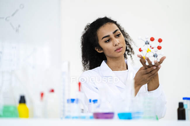Joven investigadora analizando modelo de molécula en laboratorio - foto de stock