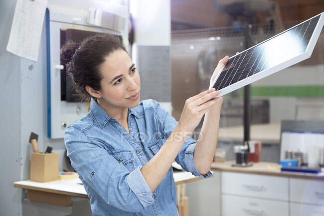 Empresaria examinando modelo de panel solar en fábrica - foto de stock