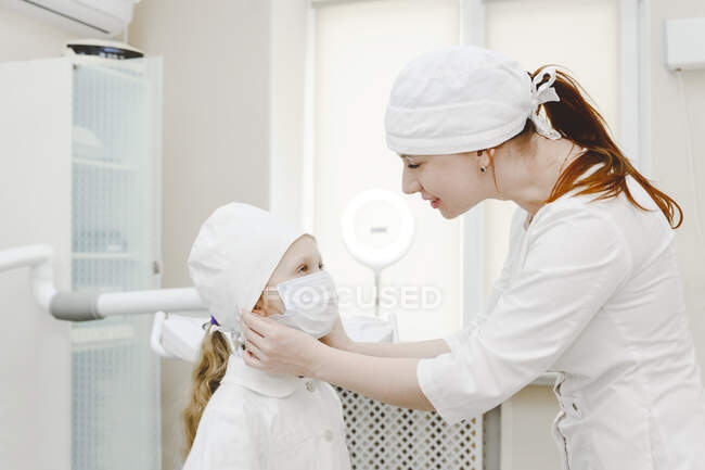 Dentiste femelle portant un masque protecteur sur la petite fille — Photo de stock