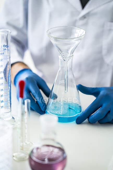 Ученый держит химическую колбу с воронкой в лаборатории — стоковое фото