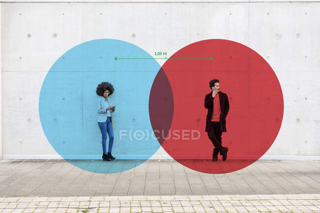 Zwei sich überlappende Kreise visualisieren die soziale Distanzierung zwischen Mann und Frau, die mit Smartphones in der Hand im Freien stehen — Stockfoto