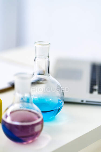 Vasos con solución química en la mesa del laboratorio de química - foto de stock