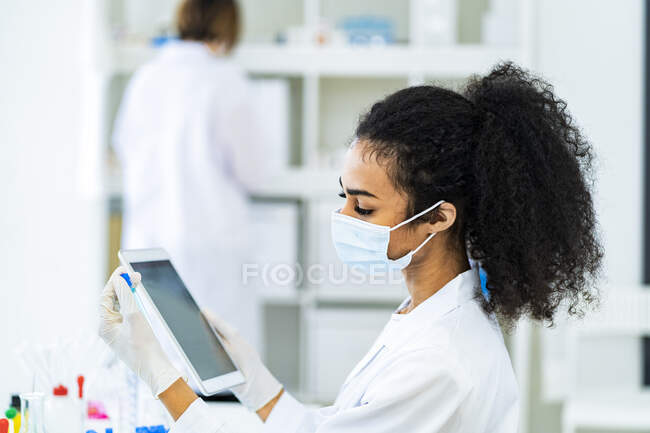Joven investigadora con tableta digital y tubo de ensayo trabajando en el hospital - foto de stock
