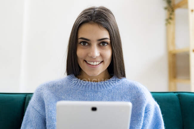 Junge Frau mit digitalem Tablet lächelt zu Hause — Stockfoto