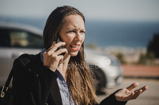 Сердита бізнес-леді розмовляє на мобільному телефоні протягом сонячного дня — стокове фото