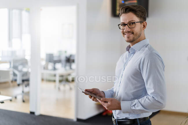 Посміхаючись чоловік - підприємець з цифровою табличкою, що стоїть на посту. — стокове фото