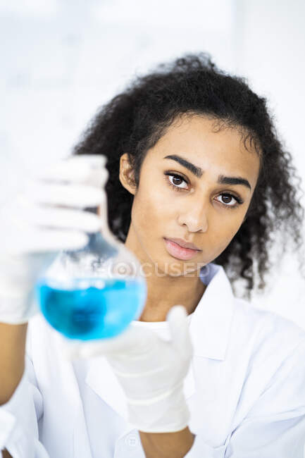 Jovem química feminina com produto químico em frasco em laboratório — Fotografia de Stock