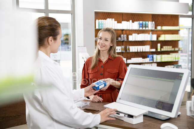 Farmacista donna che somministra medicinali alla donna al momento del checkout in negozio — Foto stock