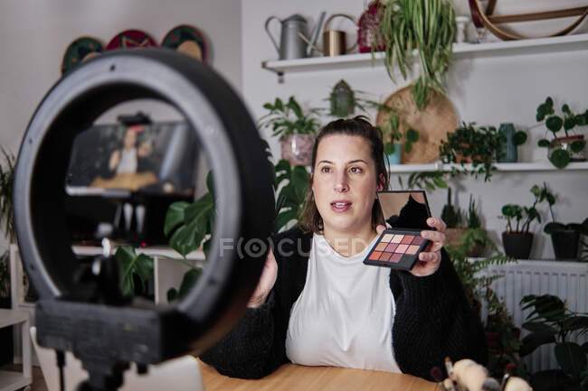 Femme vlogger montrant des produits de beauté tout en enregistrant tutoriel maquillage à la maison — Photo de stock
