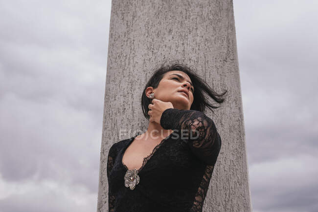 Una donna premurosa che distoglie lo sguardo mentre si trova davanti alla colonna architettonica — Foto stock