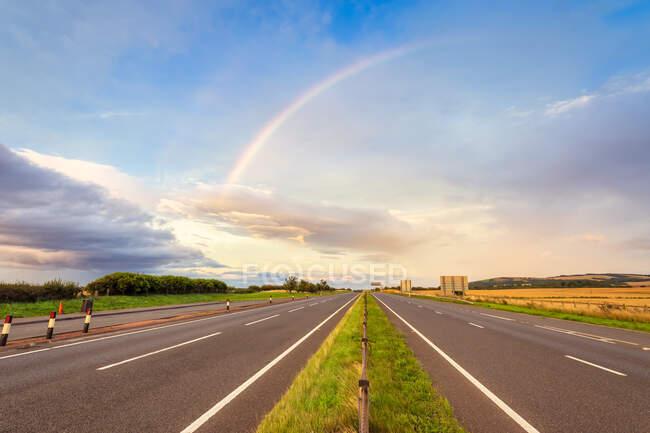 UK, Scotland, East Lothian, Double rainbow over empty highway — Stock Photo