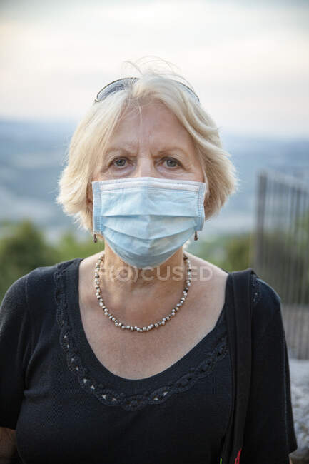 Старшая женщина в защитной маске, стоящая на улице во время COVID-19 — стоковое фото