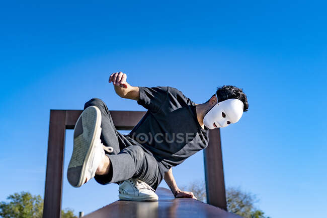 Hombre con máscara blanca bailando en muro de contención - foto de stock