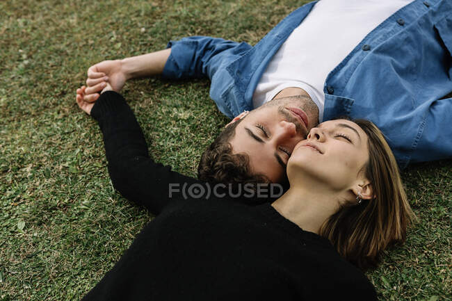 Couple souriant allongé sur la pelouse — Photo de stock