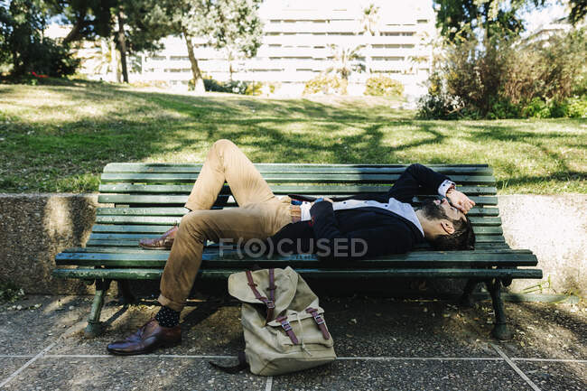 Empresário descansando enquanto estava deitado no banco no parque — Fotografia de Stock