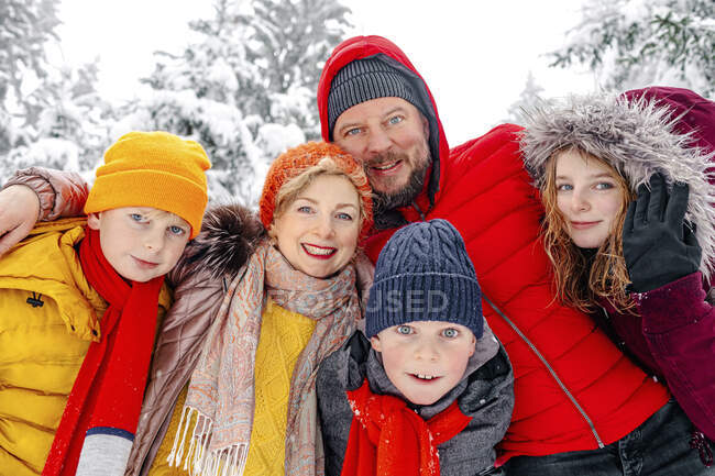 Família sorrindo de pé com o braço em volta uns dos outros na floresta — Fotografia de Stock