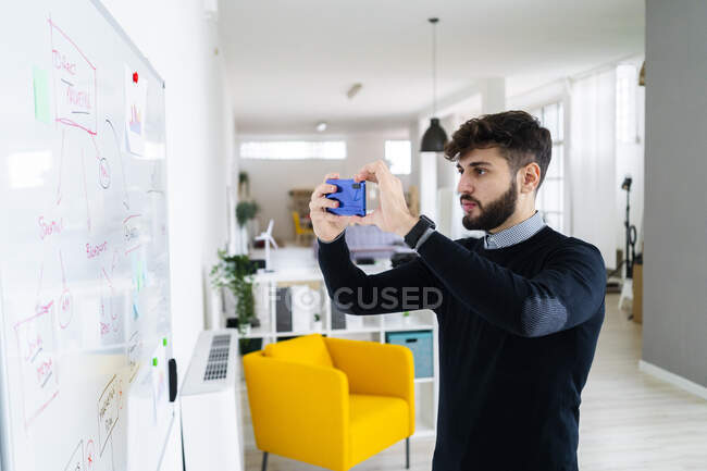 Empresário fotografando quadro branco com telefone inteligente no escritório — Fotografia de Stock