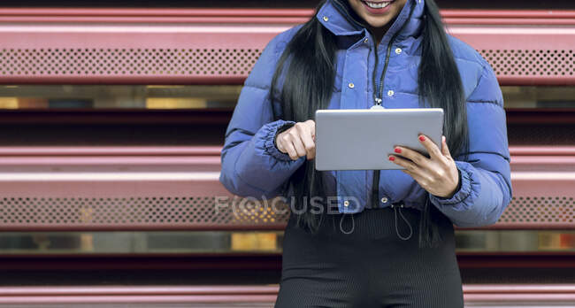 Femme souriante utilisant une tablette numérique tout en se tenant contre la rampe — Photo de stock