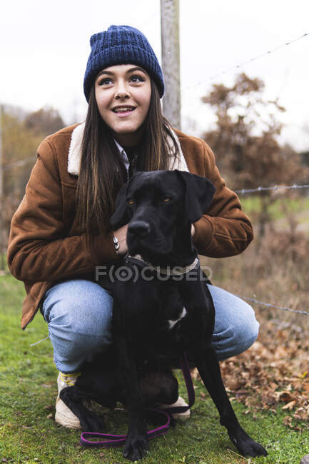 Giovane donna con cane nel paesaggio autunnale — Foto stock