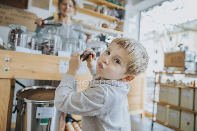 Little boy puckering while having chocolate in candy store — Stock Photo