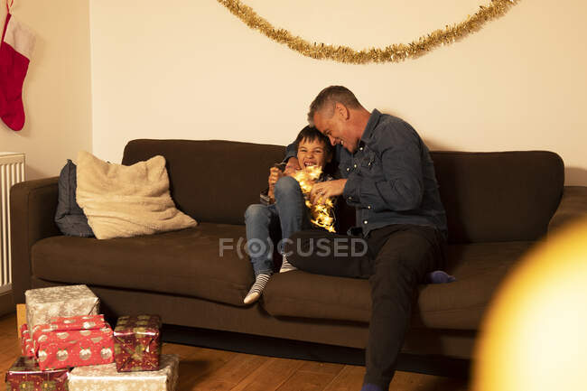 Cheerful father playing with son on sofa at home during Christmas — Stock Photo