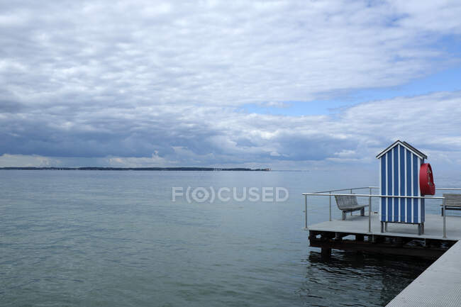 Germania, Schleswig Holstein, Stein, Molo con cabina spiaggia blu e bianca sul Mar Baltico sotto il cielo nuvoloso — Foto stock