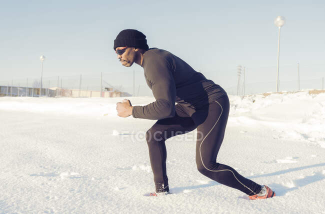 Atleta masculino correndo na neve durante o dia ensolarado — Fotografia de Stock