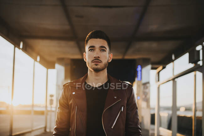 Fashionable man wearing red jacket looking away while standing in car wash tunnel — Stock Photo